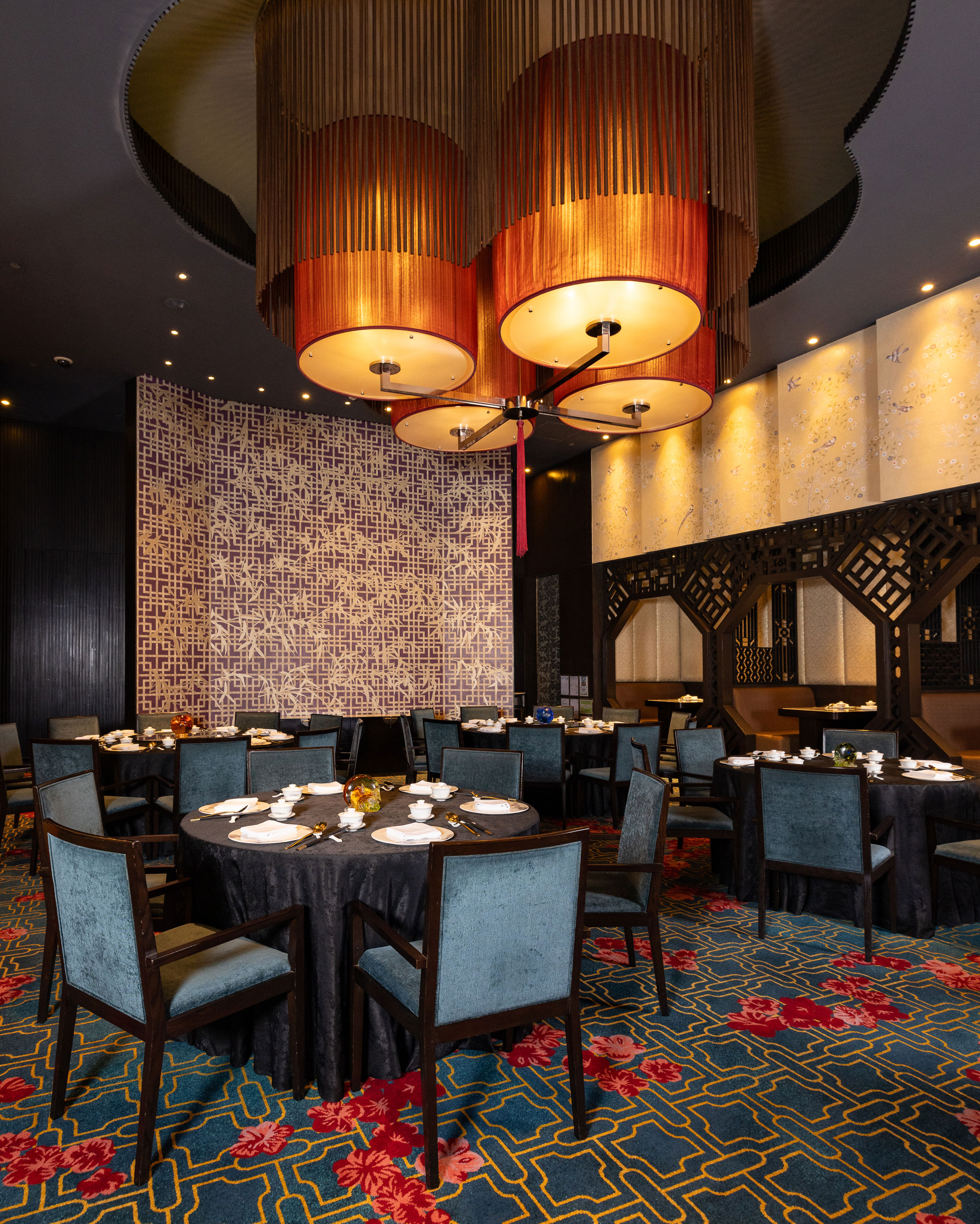 Golden-lit dining room with a crystal chandelier and round banquet tables.